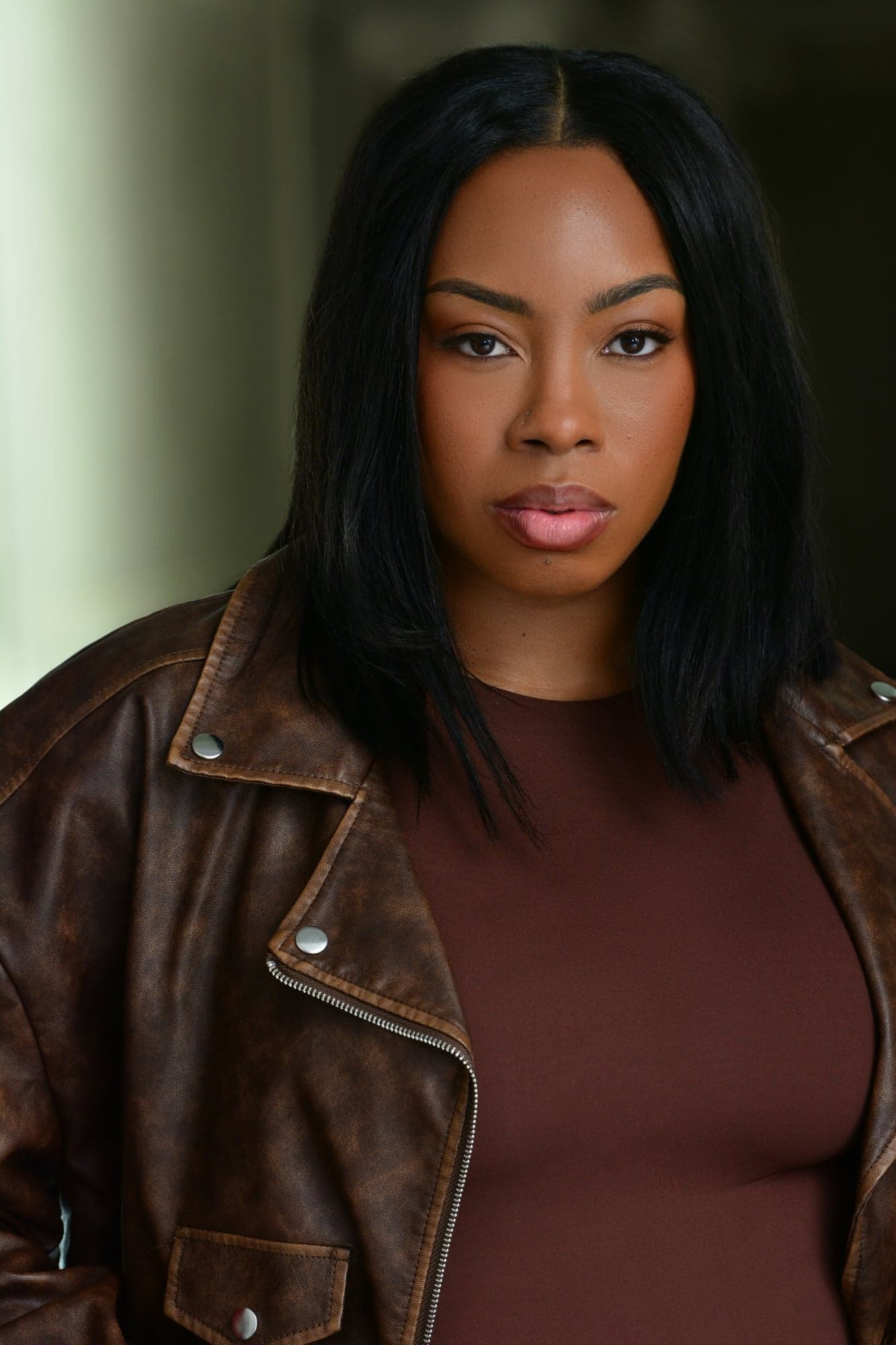 Michelle Renée Gomes headshot, brown leather jacket