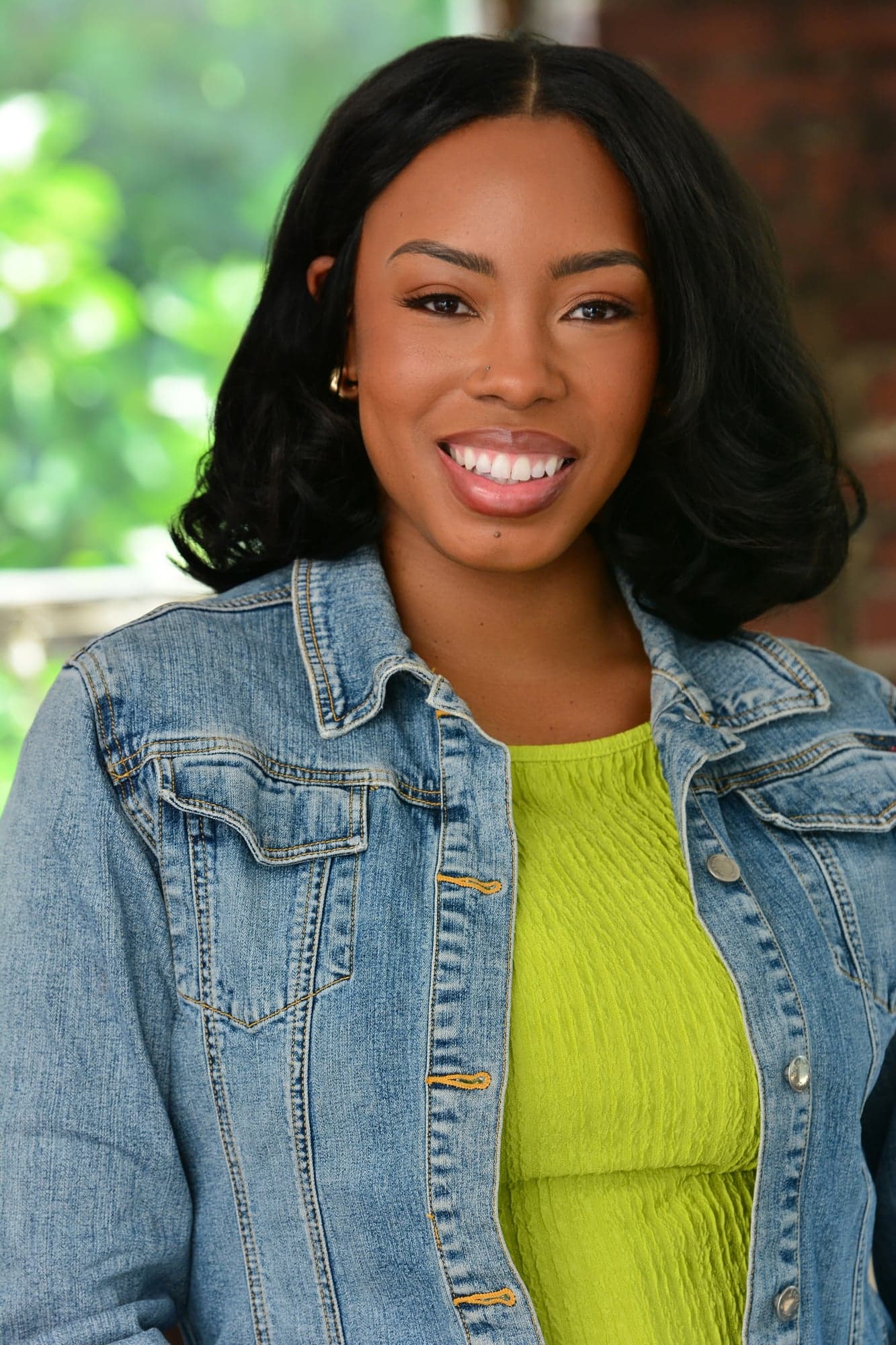 Michelle Renée Gomes headshot, smiling in a denim jacket